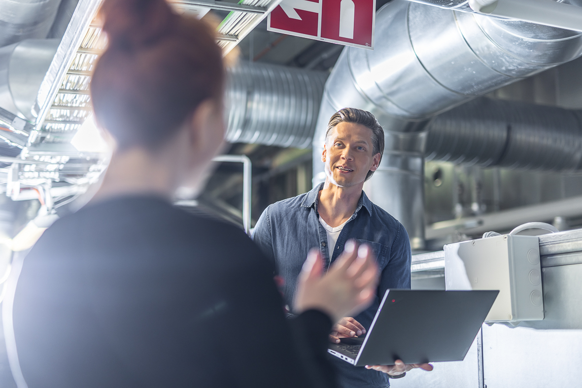 Property managers discussing real estate management issues by laptop in a technical space in an office building.